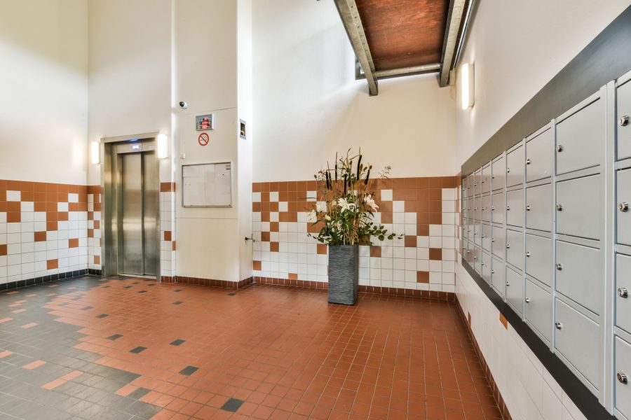 Elevator with closed door located in illuminated hall of contemporary apartment building with tiled floor